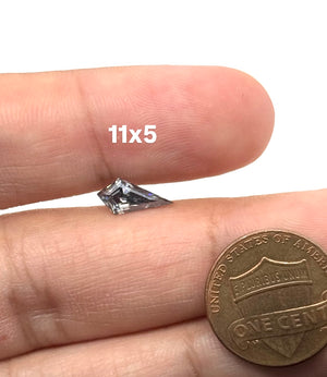 Grey kite cut moissanite gemstone measuring 11x5 mm with brilliant sparkle and elongated geometric shape.