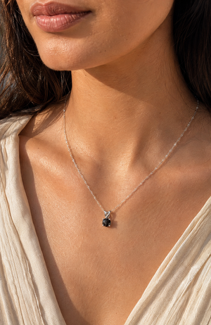 Black diamond solitaire pendant worn with an elegant outfit for anniversary jewelry styling 