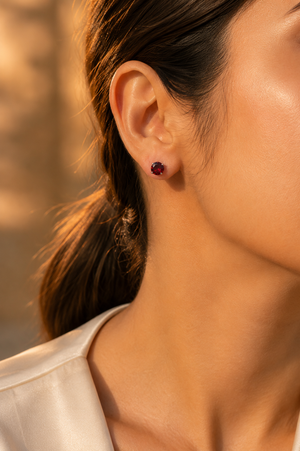 Garnet stud earrings worn on the ear for an elegant occasion