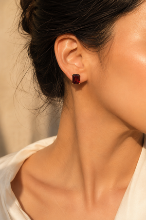 Garnet stud earrings worn on ears for an elegant evening look