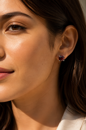 Garnet stud earrings worn on the ear as an elegant birthday jewelry look 