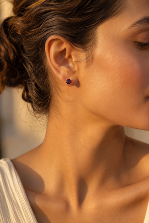 Garnet stud earrings worn on the ear with an elegant evening look 