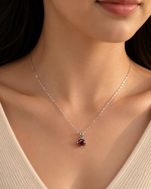 Woman wearing a Garnet solitaire necklace with elegant everyday styling.