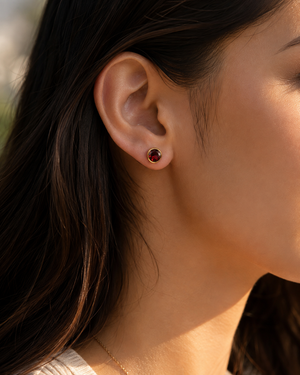 Woman wearing Garnet stud earrings styled for an elegant anniversary dinner.