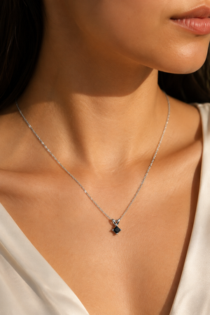 Black diamond solitaire pendant worn on the collarbone with an elegant everyday outfit princess cut black diamond pendant 