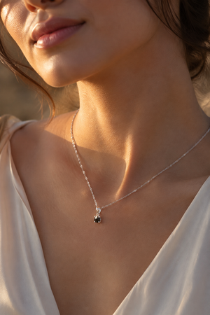 Black diamond pendant worn with an evening outfit featuring a 14K white gold solitaire necklace 