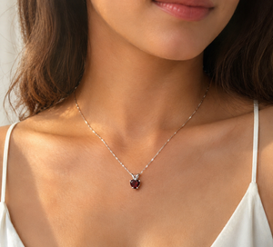 Woman wearing Garnet heart pendant with elegant evening attire.