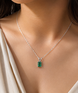 Woman wearing platinum emerald pendant necklace for elegant emerald pendant styling 