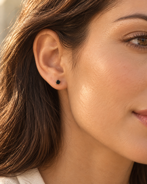 Princess cut black diamond stud earrings worn on ear with 18K yellow gold black diamond styling 