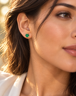 Natural emerald stud earrings worn on ear for elegant styling in 18K yellow gold emerald earrings 
