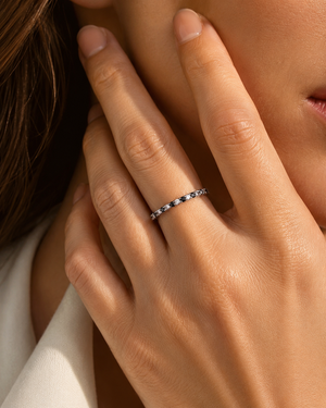 Black and white diamond eternity ring worn on a woman's hand showing a refined 14K white gold diamond band 