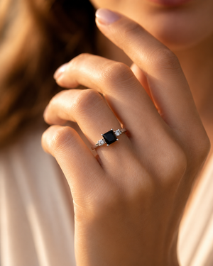 Black diamond three stone ring worn on a woman’s hand for an anniversary, an 18K white gold black diamond ring 