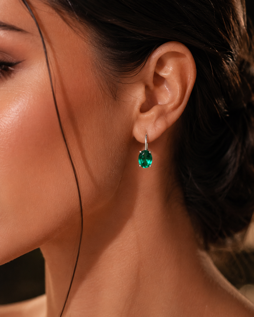 Emerald earrings worn for elegant evening styling with oval emerald stud earrings 