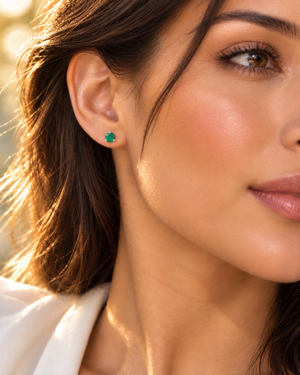 Natural emerald studs worn on the ears for an elegant anniversary jewelry look