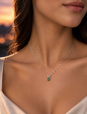 Petite emerald pendant resting at the neckline for an elegant everyday jewelry look