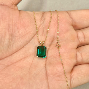 Emerald-cut green lab created emerald solitaire in polished 14K yellow gold, shown at true pendant scale on a fine chain. 