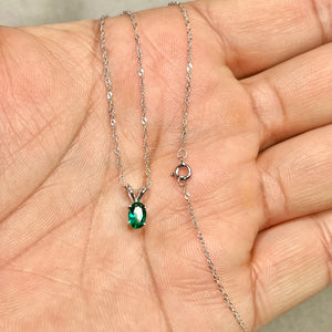 Oval green lab emerald solitaire pendant in polished 14K white gold, showing smooth prongs and slim chain scale 