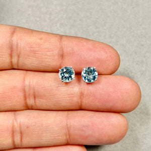 Women’s aquamarine stud earrings with two 7 mm round light blue AAA gemstones set in polished 14K white gold. Four-prong setting highlights clarity, symmetry, and clean metal edges. 
