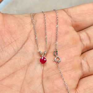 0.65 carat round dark red ruby in a four-prong platinum solitaire pendant, showing polished prongs, smooth metal finish, and scale against a fine white gold chain. 