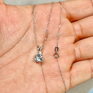 Platinum aquamarine pendant with 7 mm round light blue AA gemstone, subtle white diamond accent, and polished sculptural prong setting on a fine chain. 