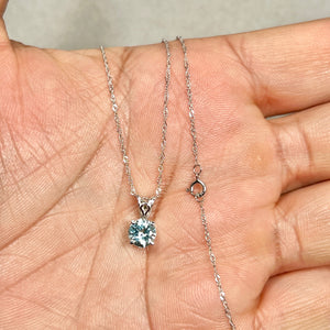 Light blue round aquamarine solitaire pendant in 14K white gold with sculptural scroll prong setting on an 18-inch Singapore chain 