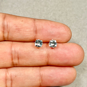 Pair of 14K white gold stud earrings with 5 mm cushion checkerboard aquamarine stones showing light blue facets and polished prongs for scale reference. 