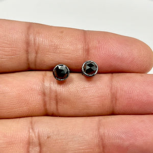 Men’s stud earring crafted in 14K blackened white gold featuring a single AAA round rose cut black diamond. The 4.5 mm bezel-set diamond weighs approximately 0.43–0.52 carats and displays a deep black tone with refined surface texture. Finished with rhodium plating and secured with push back closure for a clean, modern men’s jewelry profile 