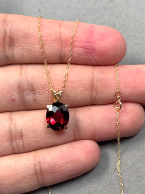 Oval garnet scroll pendant in 14K yellow gold