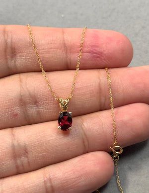 Oval garnet scroll pendant in 14K yellow gold