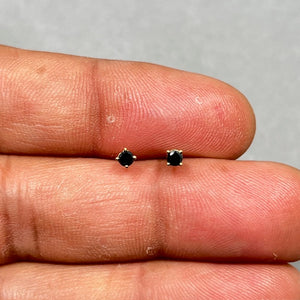 AAA round black diamond stud earrings set in 18K yellow gold, featuring two 2.5–3.0 mm prong-set black diamonds with push back closure, designed for women who prefer clean, minimal fine jewelry styling. 