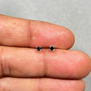 Platinum black diamond stud earrings featuring two AAA quality round black diamonds in a secure four prong setting, measuring 2.50–3.00 mm, finished with push back closures, designed for a refined and modern everyday look. 