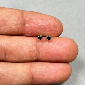 AA round black diamond stud earrings set in platinum, featuring two 2.50–3.00 mm diamonds in classic four prong settings with secure push backs. Minimal women’s diamond studs with a refined, modern finish.