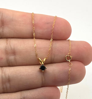 Close-up of princess-cut black diamond pendant in 14K yellow gold