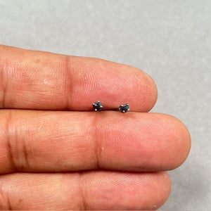 AA round rose cut black diamond stud earrings set in 14K blackened white gold with four prong setting and push back closure, featuring 2.5–3.0 mm diamonds with a total weight of 0.09–0.12 carats, designed for a bold modern look. 