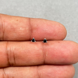 AA round black diamond stud earrings set in 14K white gold with a secure three prong setting. Features two 2.50–3.00 mm black diamonds totaling approximately 0.09–0.12 carats with a polished finish and classic push back closure. 