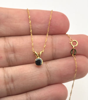 Side view of a bezel set black diamond pendant in polished 14K yellow gold craftsmanship  