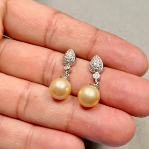 Matching pair of golden pearl earrings arranged together