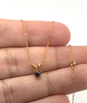 Petite black diamond solitaire showing approximately 0.23–0.30 carat gemstone size for scale