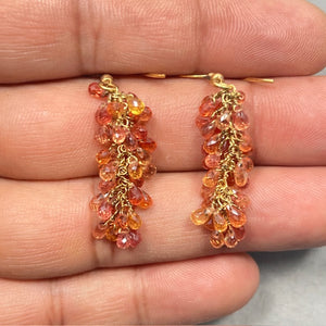 18.06 carat multi sapphire briolette earrings crafted in solid 18K yellow gold featuring natural AA quality orange sapphires in warm light to dark tones. These elegant 1.60 inch dangle earrings are secured with French wire backs and showcase sparkling briolette cut gemstones that move beautifully with light, creating a refined luxury statement for evening wear or sophisticated everyday styling. 