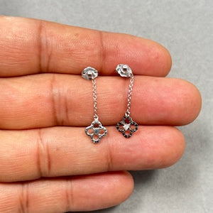 Black and white diamond clover earrings crafted in 14K white gold with rhodium finish, featuring 0.12 carat AA round black diamonds accented by sparkling white diamonds in a prong setting. These 5.5mm stud earrings hang delicately from a 1235 cable link chain and secure with post and push backs, offering a refined contrast and elegant everyday sparkle for women. 