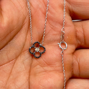 Elegant 0.15 carat black and white diamond pendant crafted in 14K white gold with rhodium finish. Features 28 round AA black diamonds totaling 0.09 carats accented by a 0.05 carat white diamond in a secure prong setting. Suspended from an 18 inch white gold rope chain, this lightweight 0.55 gram fine jewelry necklace offers modern contrast sparkle for everyday wear or formal occasions. 