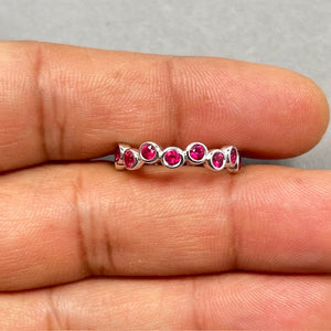 0.91 carat ruby seven stone stack band ring in solid 14K white gold, featuring seven 3mm round AA quality natural rubies in deep dark red hue. Bezel set gemstones create a sleek modern finish with secure setting and polished rhodium shine. Size 6 elegant stacking band designed for daily wear, layering, or worn solo for a refined statement look 