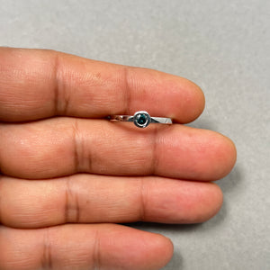 0.20 Ct natural teal blue round diamond stack band in 14K white gold, bezel set with a slim 1.9mm band and rhodium finish. Ring size 7 featuring AA-quality treated blue diamond with modern minimalist styling, perfect for stacking or wearing alone. 