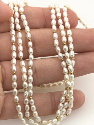 Flat lay of layered freshwater cultured pearls with warm yellow gold accents and classic fine jewelry styling 
