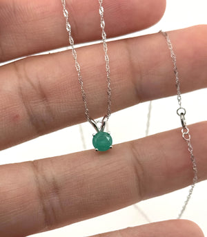 White gold emerald pendant viewed from the side with four-prong details and polished finish