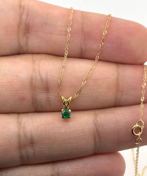 Yellow gold emerald pendant side view showing four prongs and polished scroll-inspired craftsmanship
