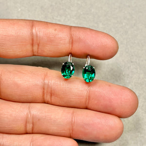 Flat lay jewelry styling with floral props and emerald green stones 