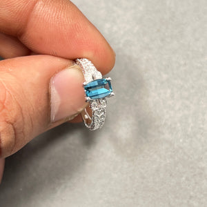 Elegant 14K White Gold women’s ring featuring a 7x5mm barrel-cut AAA Light London Blue Topaz, accented with sparkling 0.04 Ct round diamonds. Smooth rhodium finish enhances brilliance. Size 5.5, prong-set gemstones for durability. A sophisticated piece perfect for daily wear, special occasions, or adding serene blue elegance to any jewellery collection. 