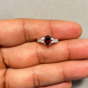 AAA barrel-cut natural garnet ring in solid 14K white gold with rhodium finish, featuring 1.25 carat deep red gemstone accented by 0.04 carat round diamonds. Elegant prong setting enhances brilliance while the slim 2–2.5 mm band offers a refined, modern silhouette. Women’s garnet diamond ring in size 4.5 designed for everyday wear or special occasions. 