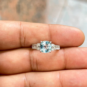 14K white gold aquamarine filigree ring featuring an 8mm cushion checkerboard-cut natural aquamarine gemstone weighing approximately 1.94 carats, accented with round diamonds totaling 0.04 carats. Antique-inspired filigree detailing with rhodium finish enhances brilliance, creating an elegant vintage-style statement ring for women with serene blue hues and refined sparkle. 